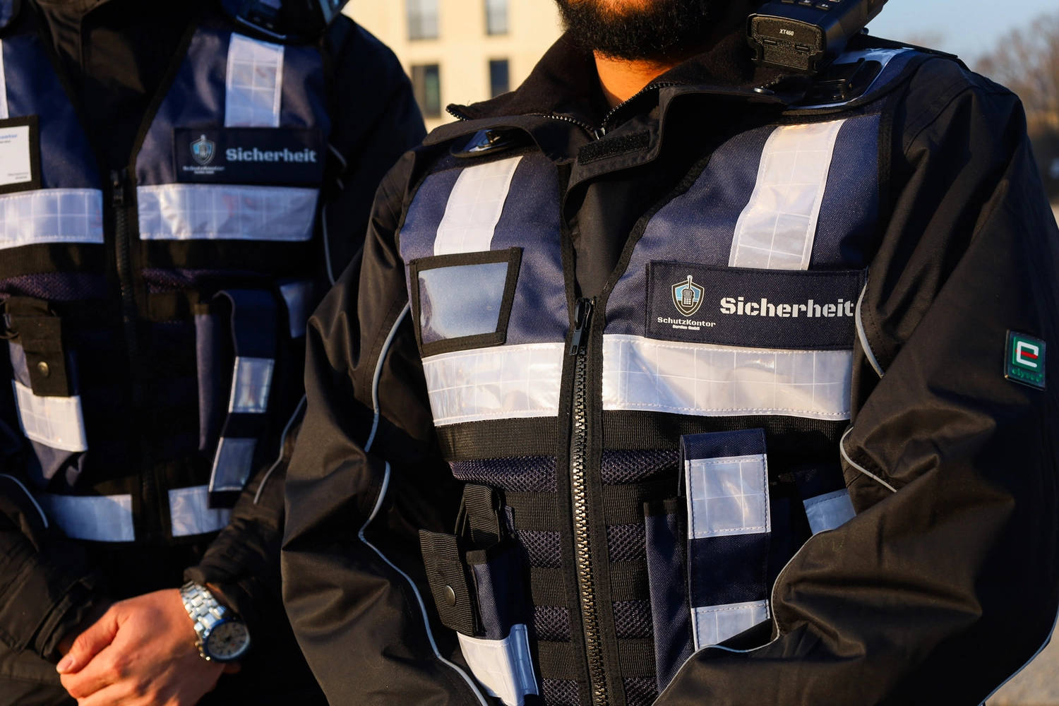 Schutzkontor Service GmbH - Sicherheitsdienst - Männlicher Wachmann benutzt im Freien ein tragbares Funkgerät