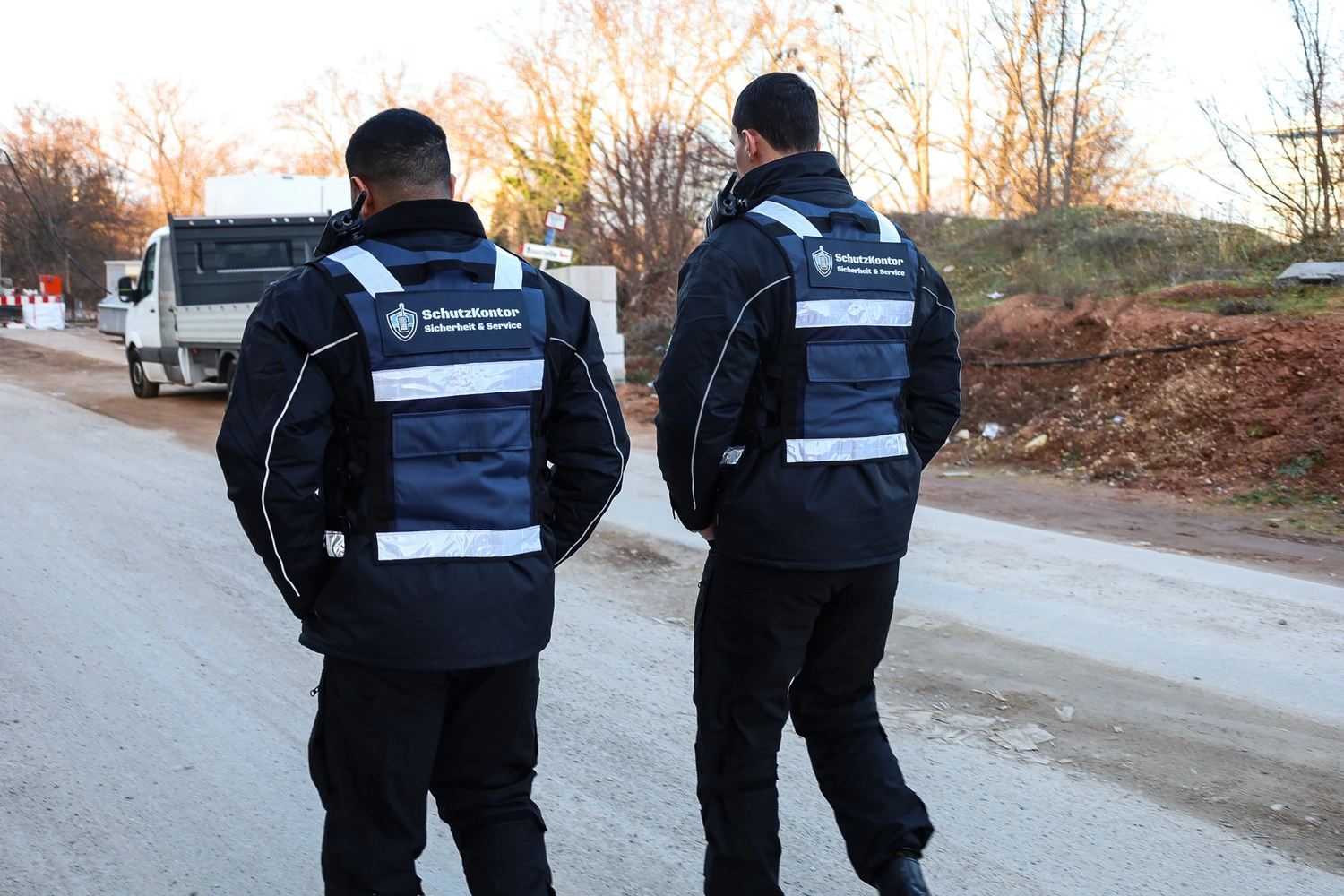 Schutzkontor Service GmbH - Sicherheitsdienst - Männlicher Wachmann benutzt im Freien ein tragbares Funkgerät