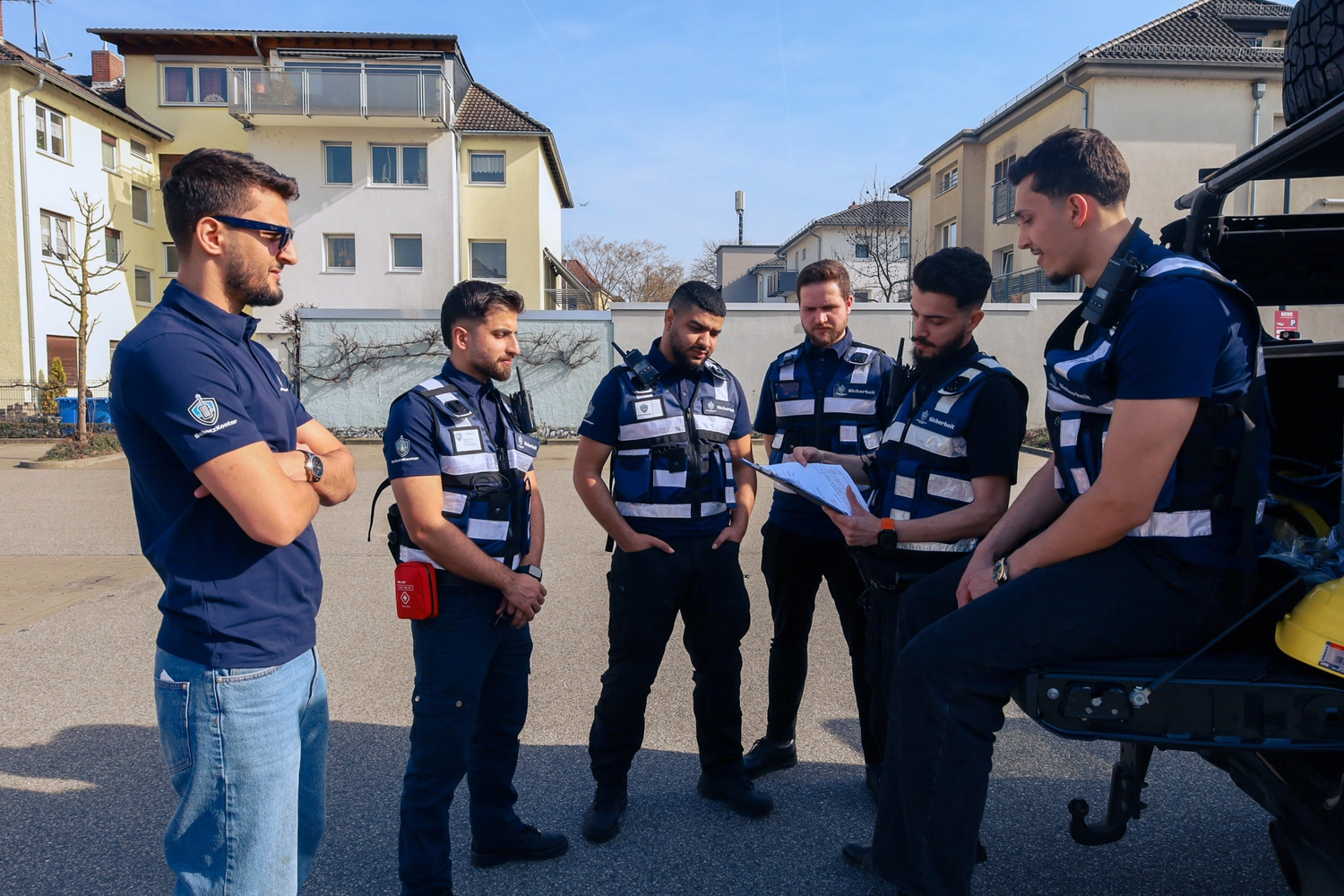 Schutzkontor Service GmbH - Sicherheitsdienst - Männlicher Wachmann benutzt im Freien ein tragbares Funkgerät