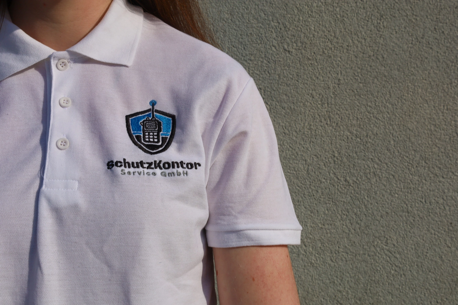 Schutzkontor Service GmbH - Sicherheitsdienst - Männlicher Wachmann benutzt im Freien ein tragbares Funkgerät